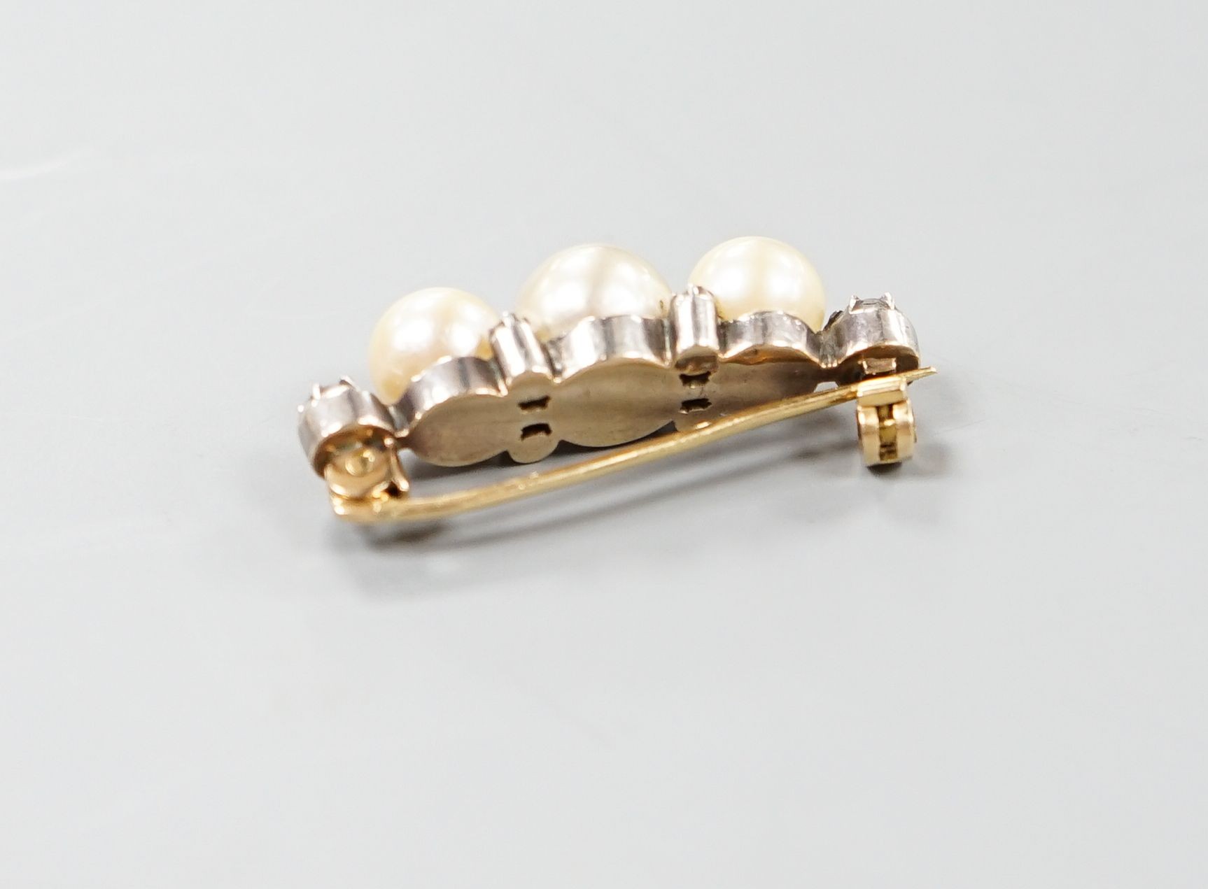 A yellow metal, three stone cultured pearl and six stone diamond brooch, 34mm, gross weight 8.1 grams.